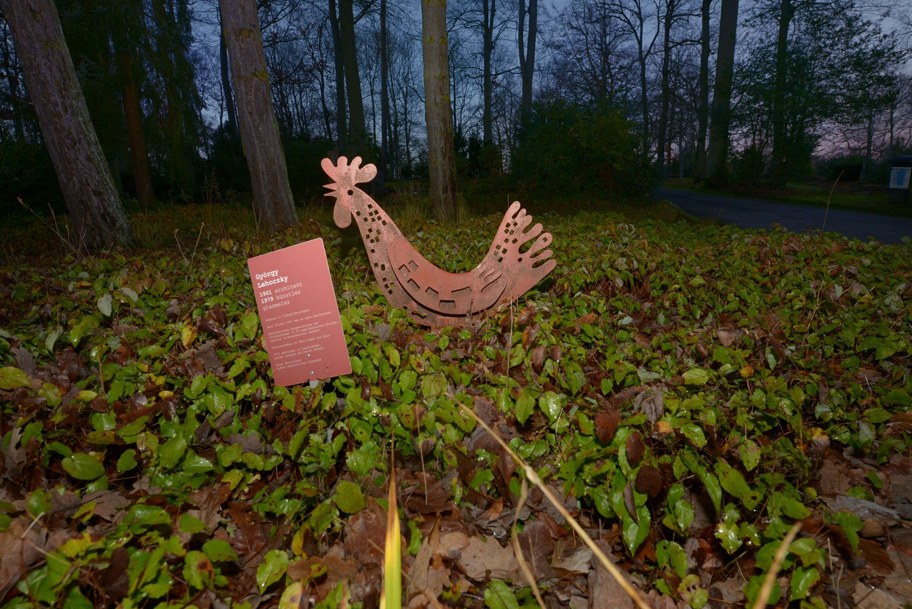 Metallener Hahn an der Grabstätte von György Lehoczky im Waldlaub auf Hauptfriedhof Saarbrücken